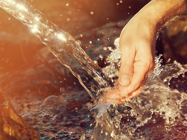 Hand im frischen, von oben strömenden, Wasser